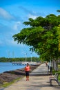 Black woman runs along the city promenade. Jogging on the ocean coast