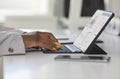 Black woman sitting at desk in office and typing on keyboard of her tablet computer Royalty Free Stock Photo