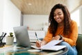 Black woman sitting at desk, using computer writing in notebook Royalty Free Stock Photo