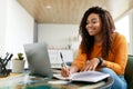 Black woman sitting at desk, using computer writing in notebook Royalty Free Stock Photo