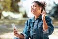 Black Woman With Smartphone Listening Music In Earbuds Sitting Outdoors Royalty Free Stock Photo