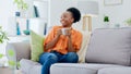 Black woman, smiling and couch with tea, relaxing and cozy home for self care, living room and break. Me time, comfort