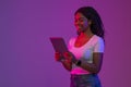 Black Woman Standing in Neon Light And Browsing Internet On Digital Tablet Royalty Free Stock Photo