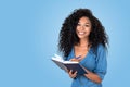 Young black woman taking notes and smiling, copy space blue background Royalty Free Stock Photo