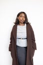 Black Woman in Stylish Brown Coat and Gray Sweater Against White Background Royalty Free Stock Photo