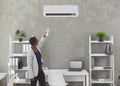 Black woman uses a remote control to switch on the air conditioner in the office Royalty Free Stock Photo