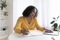 Black woman using laptop, working or studying online, taking notes during video conference or webinar at home Royalty Free Stock Photo