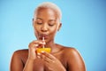 Black woman, vitamin C and drinking orange for diet or natural nutrition against a blue studio background. Calm African Royalty Free Stock Photo