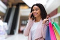 Black woman walking in mall with shopping bags and talking on cellphone Royalty Free Stock Photo