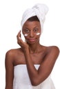 Black woman wrapped in towel moisturizing face Royalty Free Stock Photo