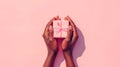 Black woman\'s hands holding a present gift box with bow against a light pink background. Overhead view. Close up. Mothers Royalty Free Stock Photo