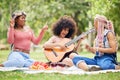 Black women, friends and picnic in park with guitar playing music, singing and spending time together. Comic, funny and Royalty Free Stock Photo