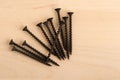 Black wood screws on wooden background. Royalty Free Stock Photo