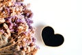 Black woodden heart with dry flower on white