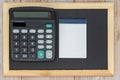 Black wooden blackboard, calculator and electronic blank paper notebook. Top view. Copy space. Taxes, mathematics, investments,