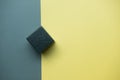 Black wooden cube against black and yellow background