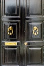 Black wooden door with golden vintage knockers and mail slot letterbox Royalty Free Stock Photo