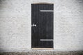 Black wooden door on a grey brick wall Royalty Free Stock Photo