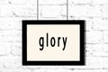 Black frame hanging on white brick wall with inscription glory Royalty Free Stock Photo