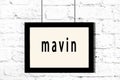 Black frame hanging on white brick wall with inscription mavin