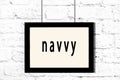 Black frame hanging on white brick wall with inscription navvy Royalty Free Stock Photo