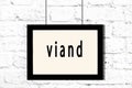 Black frame hanging on white brick wall with inscription viand