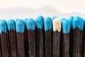 Black wooden matches with bright blue heads and one match with white head. Matchsticks without box close-up