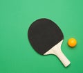 Black wooden racket and plastic orange table tennis ball, top view Royalty Free Stock Photo