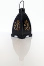 A black wrought iron lantern of Indian origin with the light on, isolated on a white background with reflection Royalty Free Stock Photo