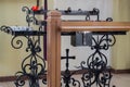 Black wrought metal pedestal for Church candles with flourishes on edges, cross and donation box in middle, prayer stand in front