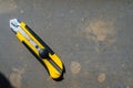 A black and yellow paper knife laying on textured stone table Royalty Free Stock Photo