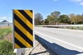 Black and yellow warning sign on a highway guardrail.