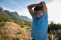 Black young Adult male looking down while stretching before his run on the mountain in the morning Royalty Free Stock Photo