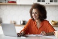 Black Young Freelancer Woman Working With Laptop In Kitchen And Taking Notes Royalty Free Stock Photo