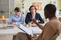 Black young man holding clipboard leading business meeting with team Royalty Free Stock Photo