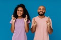 Black young man and woman making fingers crossed for best luck