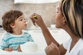 A Black Young mother feeding her baby son with fruit puree Royalty Free Stock Photo