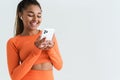 Black young sportswoman using smartphone and earphones