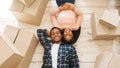Black young woman with her handsome husband lying among cardboard boxes on floor of their new home, top view Royalty Free Stock Photo