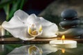 Black zen stones,candles and white orchids on a wooden plank on the surface of the water. SPA, relaxation, meditation Royalty Free Stock Photo