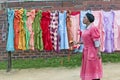 Black Zulu woman with apple strolls past a display of brightly colored dresses in Zulu village in Zululand, South Africa