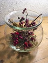 Blackberries, holly, rosehip and grasses in glass vase decorated autumnally