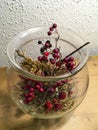 Blackberries, holly, rosehip and grasses in glass vase decorated autumnally