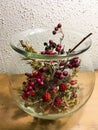 Blackberries, holly, rosehip and grasses in glass vase decorated autumnally