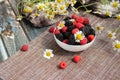 Blackberries and raspberries in a white container on a wooden background. Textile. Wild flowers, daisies. Horizontal position of Royalty Free Stock Photo