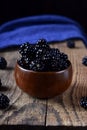 Blackberries in a wooden bowl on the wooden table