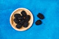 Blackberries on a wooden plate on a textured classic blue background Royalty Free Stock Photo