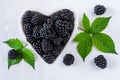 Blackberry berries in a white heart-shaped plate on a white wooden surface