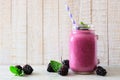 Blackberry smoothie in a mason jar with scattered berries over white wood Royalty Free Stock Photo