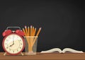 Blackboard and book, alarm clock, pencil penal on a table. School supplies on a desk. Vector Royalty Free Stock Photo